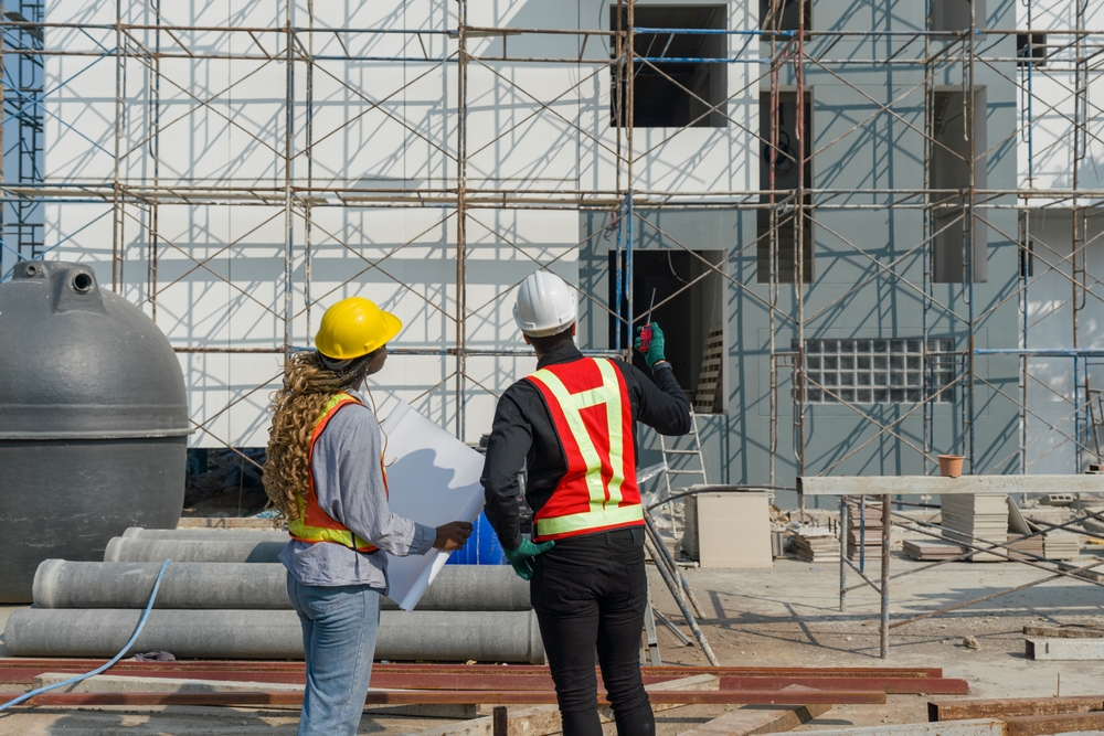 Two,construction,workers,are,standing,together,in,front,of,a